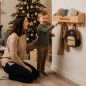 Preview: Weihnachtsszene mit Mutter und Kind, die sich über eine personalisierte Garderobe freuen; Produkt hängt an der Wand, Gravur gut lesbar, Weihnachtsbaum daneben.